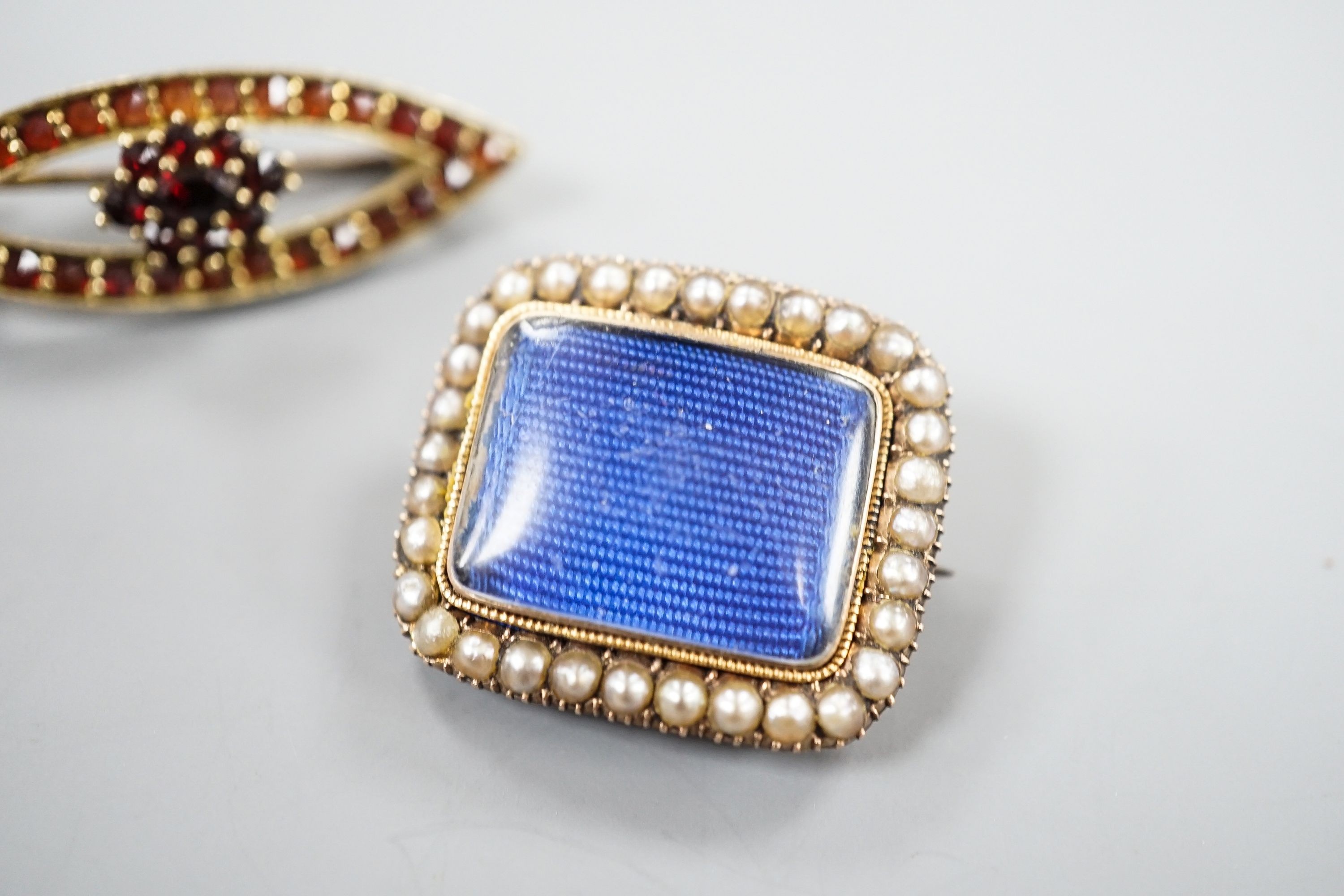 A Victorian yellow metal and spit pearl set mourning brooch, 23mm and 900 git white metal and garnet set brooch.